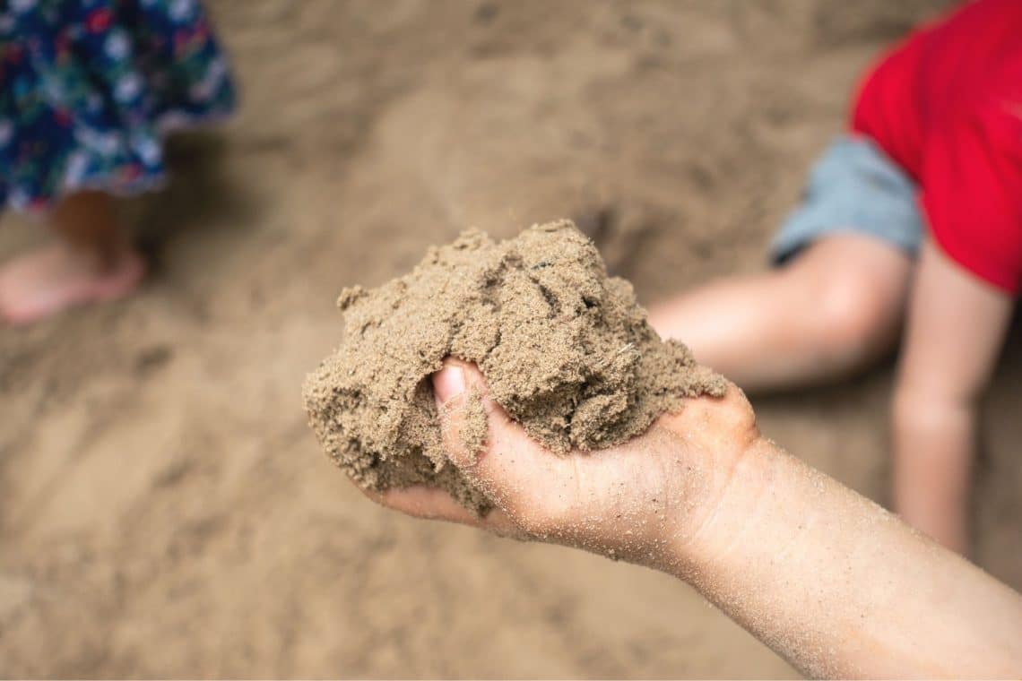 Kind hat eine Hand voll Sand im Sandkasten