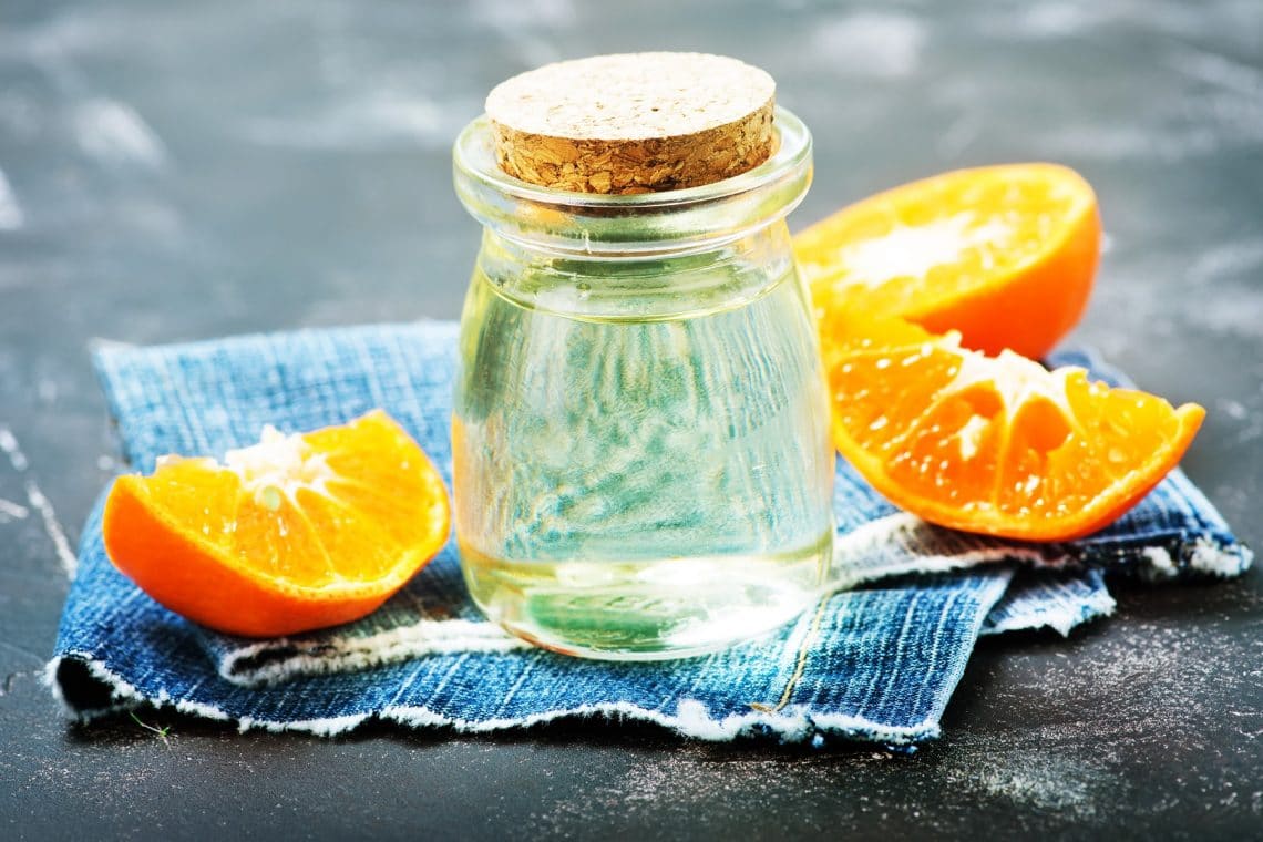 Fläschchen Orangenöl auf Tisch mit Orangenschalen