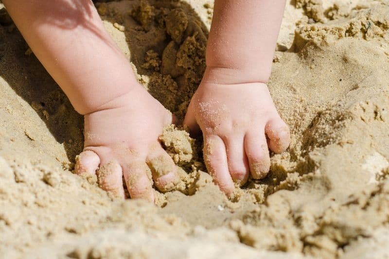 Kind spielt in Sandkasten mit Spielsand