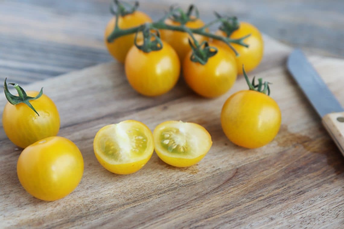 Aufgeschnittene gelbe Tomaten auf Holzbrett