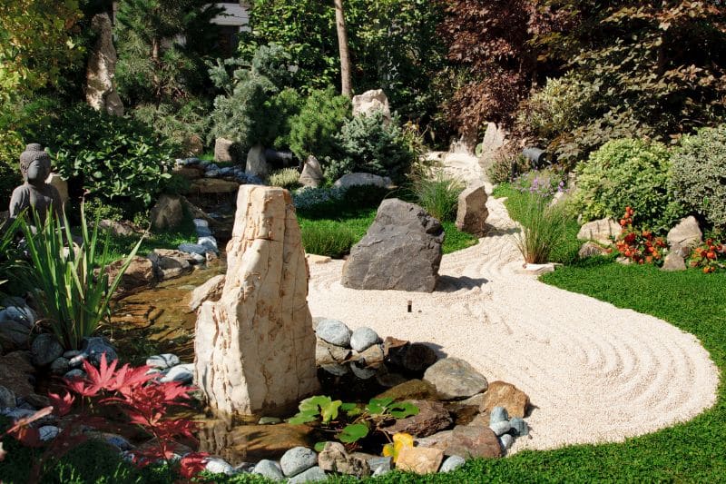 Kiesweg neben Wasserlauf mit Natursteinen in einem Garten