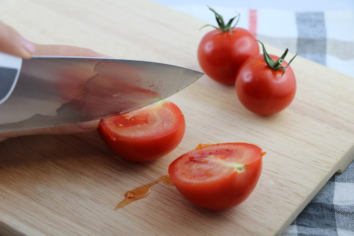 Tomaten auf einem Holzbrett schneiden